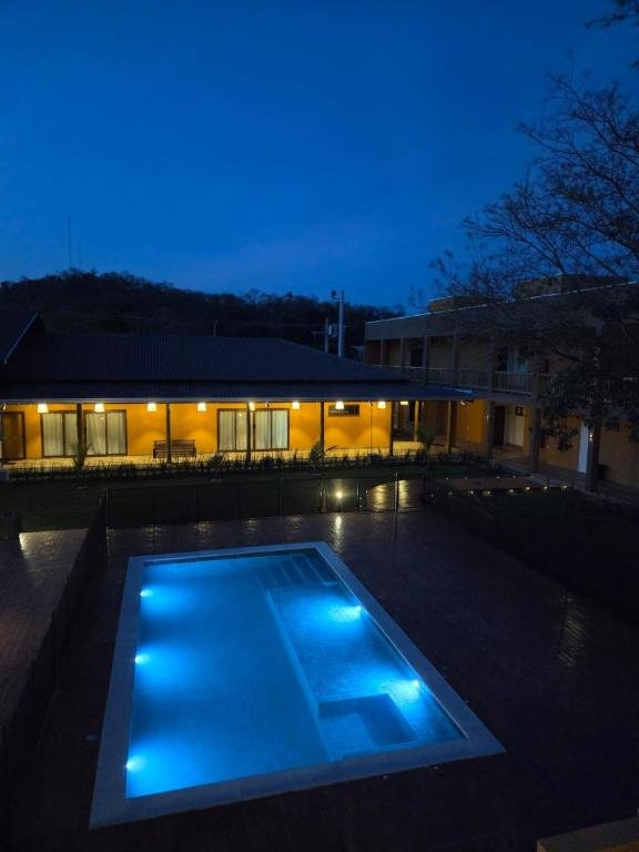 The lit pool at Pousada Maritaca at dusk, with the garden and the suites behind it